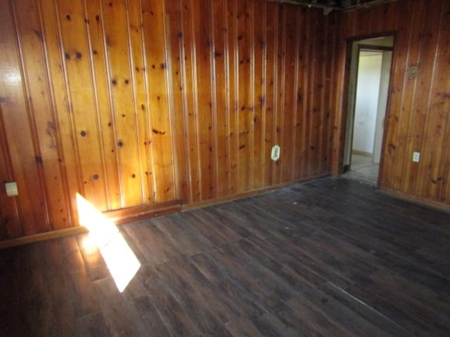 unfurnished room with wooden walls, baseboards, and wood finished floors