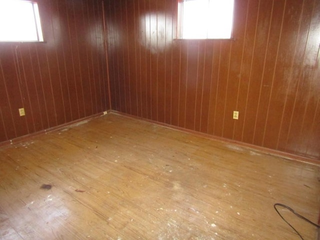 spare room with hardwood / wood-style flooring and wooden walls