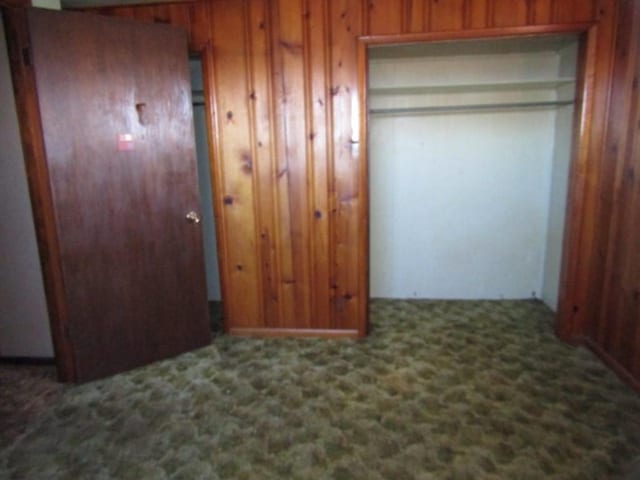 unfurnished bedroom featuring wood walls and carpet flooring