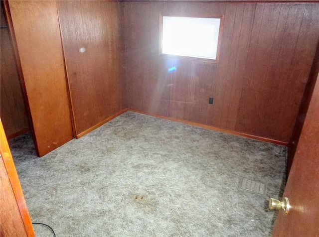 carpeted spare room with wooden walls