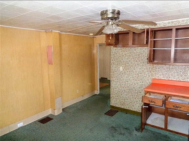 kitchen featuring ceiling fan and wood walls