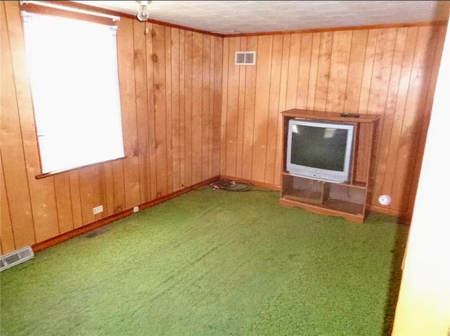 carpeted spare room with baseboards, visible vents, and wooden walls