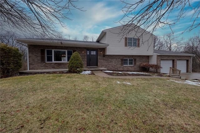 split level home with a garage, driveway, brick siding, and a front yard