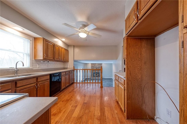 kitchen with brown cabinets, light wood finished floors, light countertops, a sink, and dishwasher