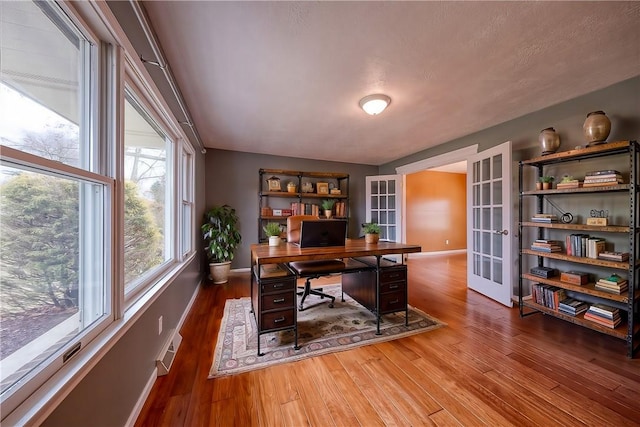 home office featuring french doors, wood finished floors, visible vents, and baseboards