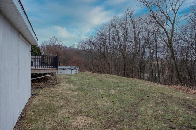 view of yard with a forest view, a covered pool, and a wooden deck