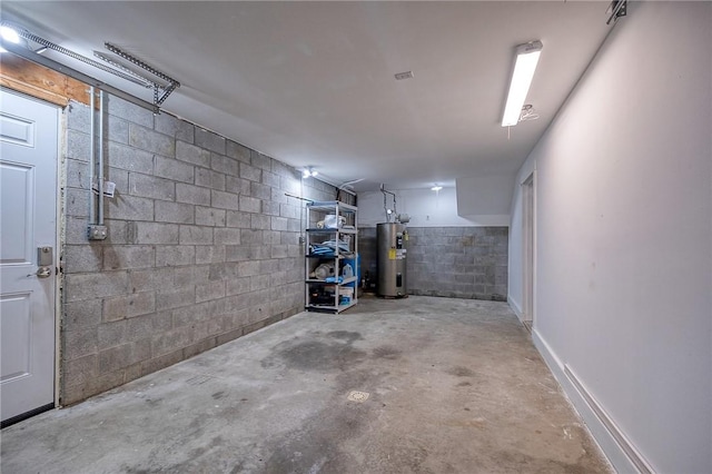 basement with a garage, concrete block wall, and electric water heater