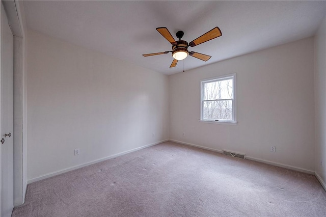 carpeted empty room with a ceiling fan, visible vents, and baseboards