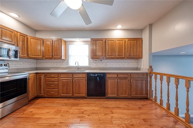 kitchen with brown cabinetry, light wood-style flooring, stainless steel appliances, light countertops, and a sink