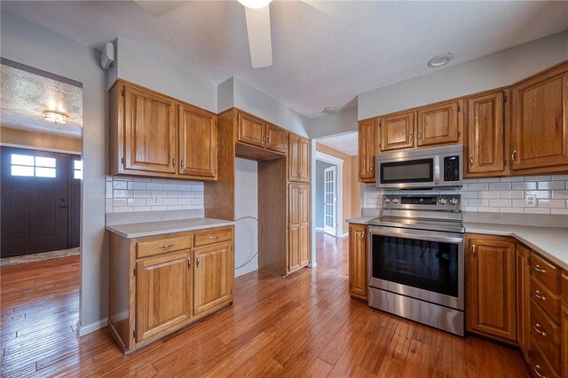 kitchen featuring brown cabinets, light wood finished floors, stainless steel appliances, and light countertops