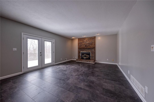 unfurnished living room with a textured ceiling, a fireplace, visible vents, baseboards, and french doors