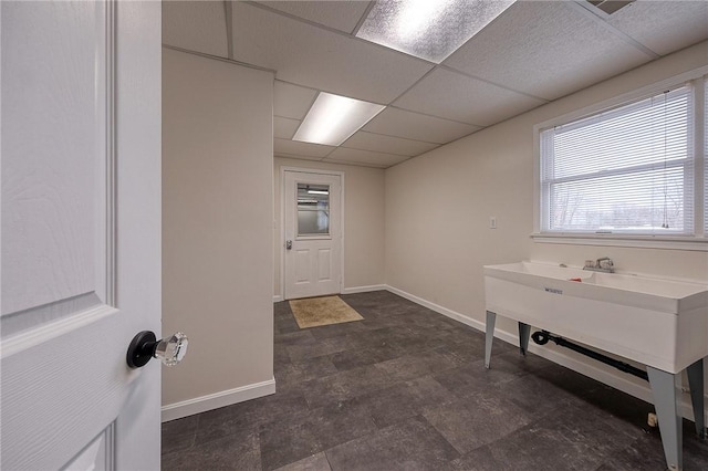 interior space featuring a drop ceiling and baseboards