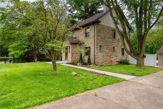 view of front of home with stone siding, fence, and a front yard