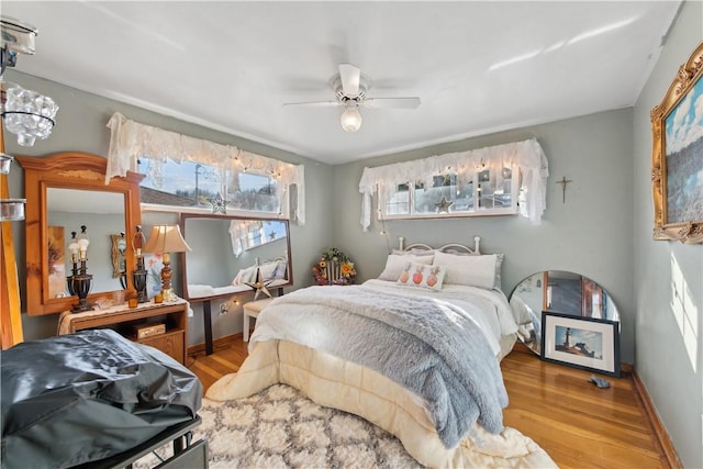 bedroom featuring ceiling fan, baseboards, and wood finished floors