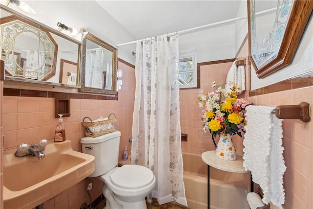 bathroom with toilet, shower / bath combo with shower curtain, a sink, and tile walls