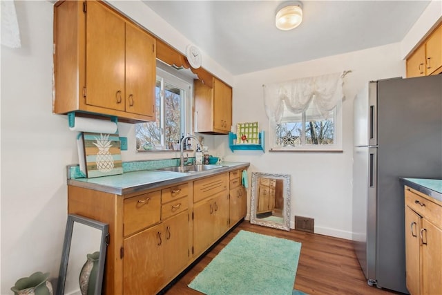 kitchen with dark wood finished floors, visible vents, freestanding refrigerator, a sink, and baseboards