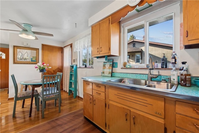 kitchen featuring baseboards, brown cabinetry, ceiling fan, dark wood-style flooring, and a sink