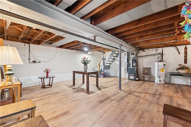 unfinished below grade area with heating unit, water heater, stairway, and wood finished floors