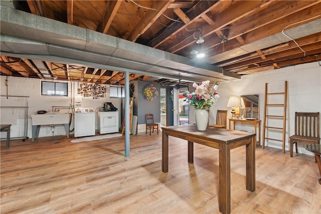 basement featuring a sink, separate washer and dryer, and wood finished floors