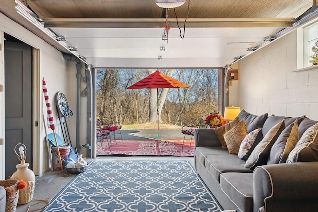 living room featuring a garage, concrete block wall, and unfinished concrete flooring