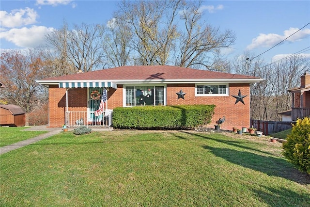 view of front of home with brick siding, fence, and a front lawn