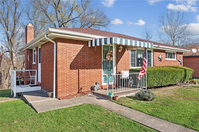 view of front facade featuring a chimney, a front lawn, and brick siding