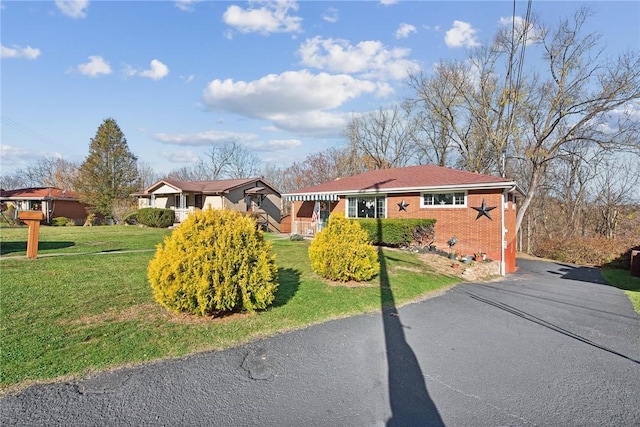 ranch-style home featuring brick siding, aphalt driveway, and a front yard