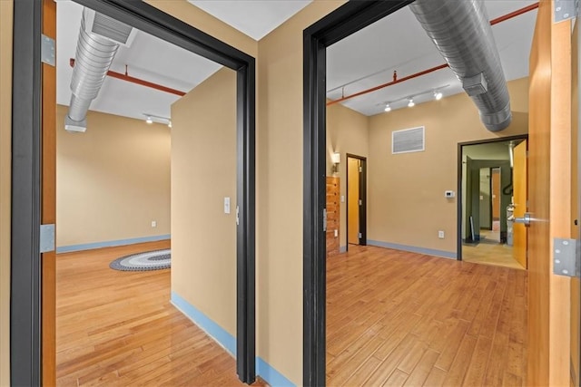 hallway with baseboards, visible vents, and hardwood / wood-style floors