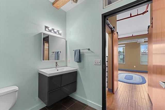 bathroom with baseboards, vanity, toilet, and wood finished floors