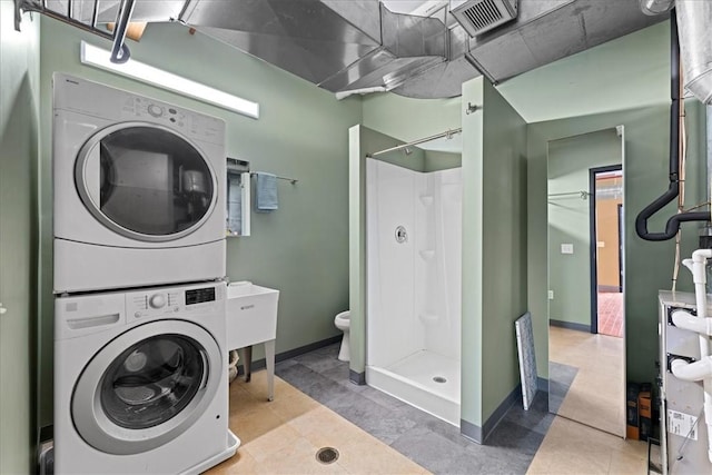 washroom with stacked washer / dryer, visible vents, and baseboards