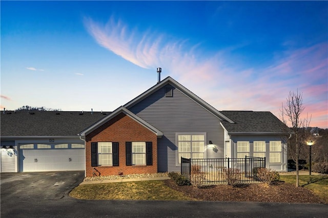 ranch-style home with a garage, aphalt driveway, roof with shingles, and brick siding