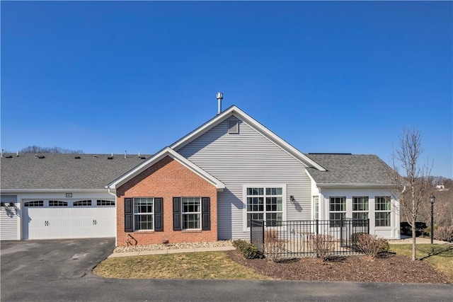 single story home featuring aphalt driveway, brick siding, a shingled roof, and an attached garage