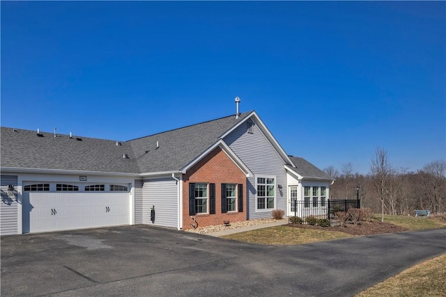 view of front of home with a garage, brick siding, fence, driveway, and roof with shingles