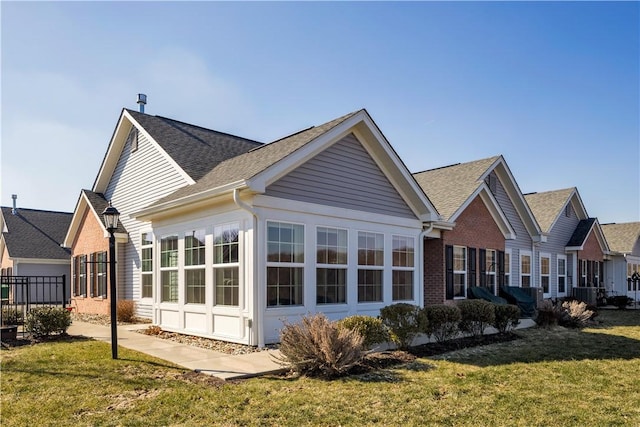 rear view of house featuring a yard, brick siding, and a shingled roof