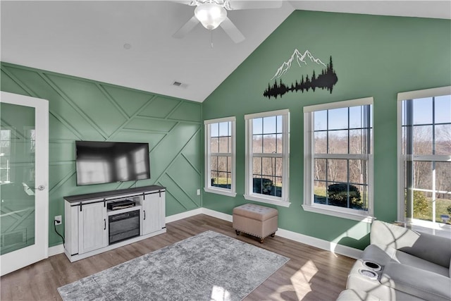 living area featuring dark wood-style floors, an accent wall, visible vents, and plenty of natural light