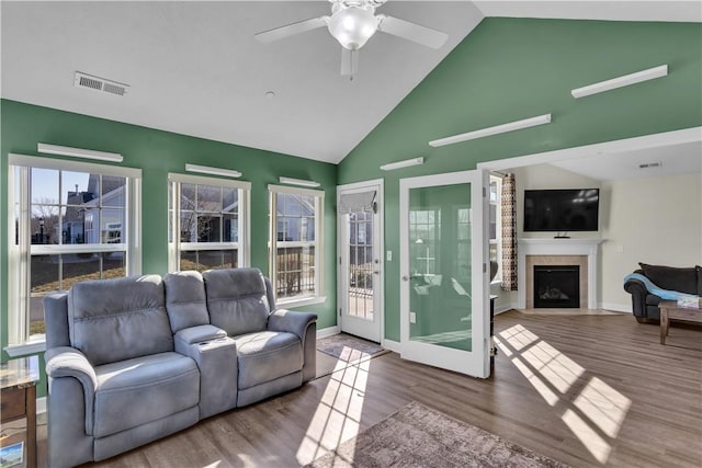 living room featuring a fireplace with flush hearth, wood finished floors, visible vents, and a ceiling fan