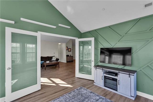 interior space with high vaulted ceiling, a wealth of natural light, wood finished floors, and visible vents