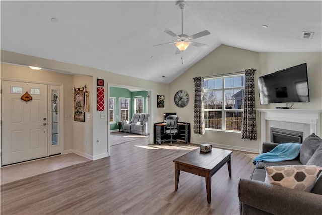 living room featuring a fireplace, lofted ceiling, visible vents, wood finished floors, and baseboards