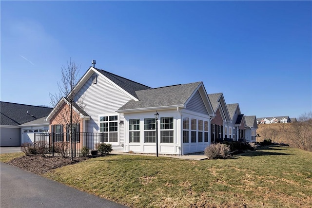 view of side of property with a lawn and roof with shingles