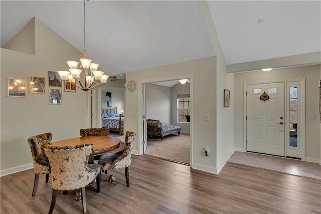 dining room with a notable chandelier, high vaulted ceiling, wood finished floors, and baseboards