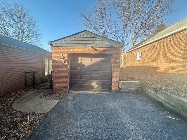 detached garage featuring fence and aphalt driveway