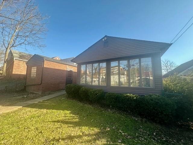 rear view of property featuring a sunroom, brick siding, and a lawn