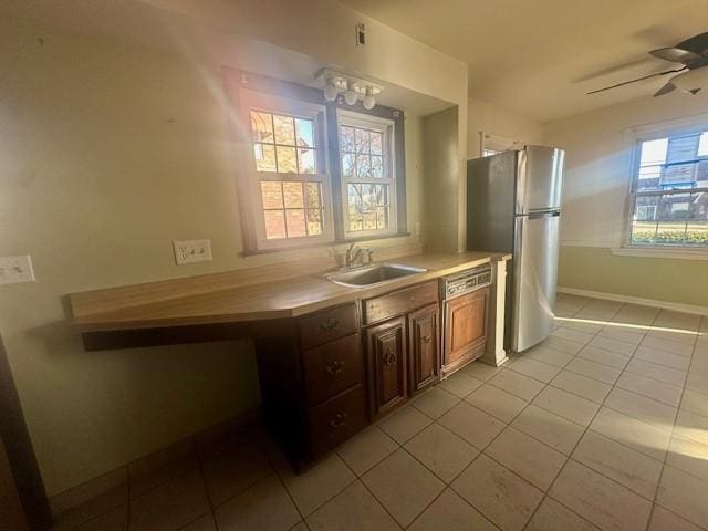 kitchen featuring light tile patterned floors, light countertops, freestanding refrigerator, ceiling fan, and a sink