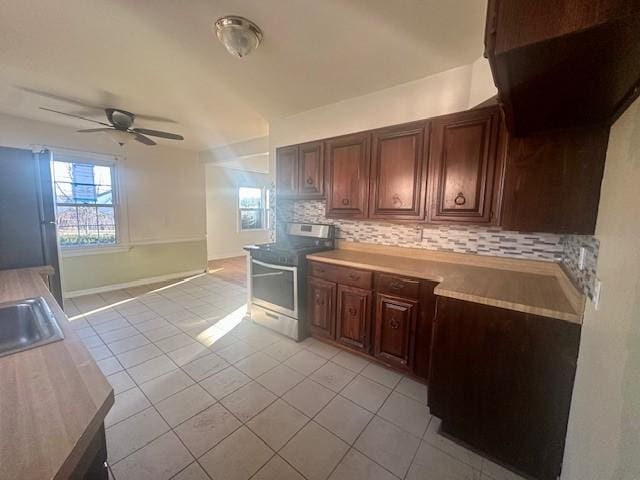 kitchen with stainless steel range with electric stovetop, light tile patterned floors, decorative backsplash, and light countertops