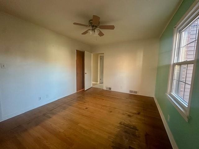 spare room featuring a ceiling fan, baseboards, visible vents, and wood finished floors