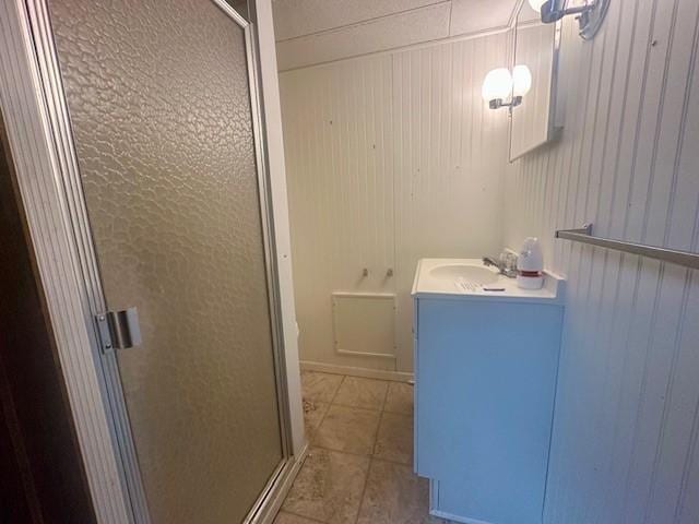 full bath featuring wooden walls, a stall shower, tile patterned flooring, and vanity