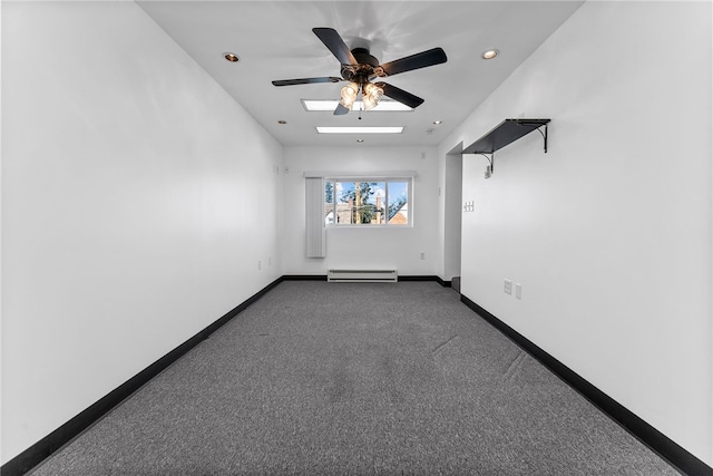 spare room with a baseboard radiator, a skylight, a ceiling fan, baseboards, and dark carpet