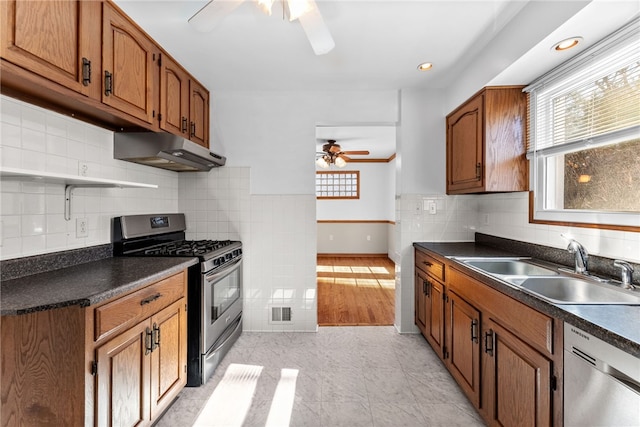 kitchen featuring ceiling fan, under cabinet range hood, a sink, appliances with stainless steel finishes, and dark countertops