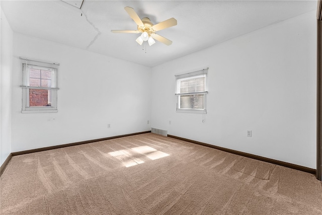 carpeted empty room with baseboards, visible vents, and a wealth of natural light