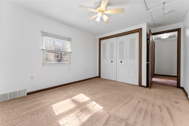 unfurnished bedroom with a closet, visible vents, attic access, light carpet, and baseboards